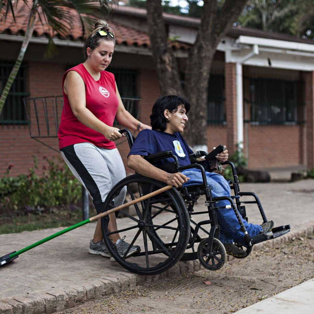 Erziehrin kümmert sich um einen Jungen im Rollstuhl