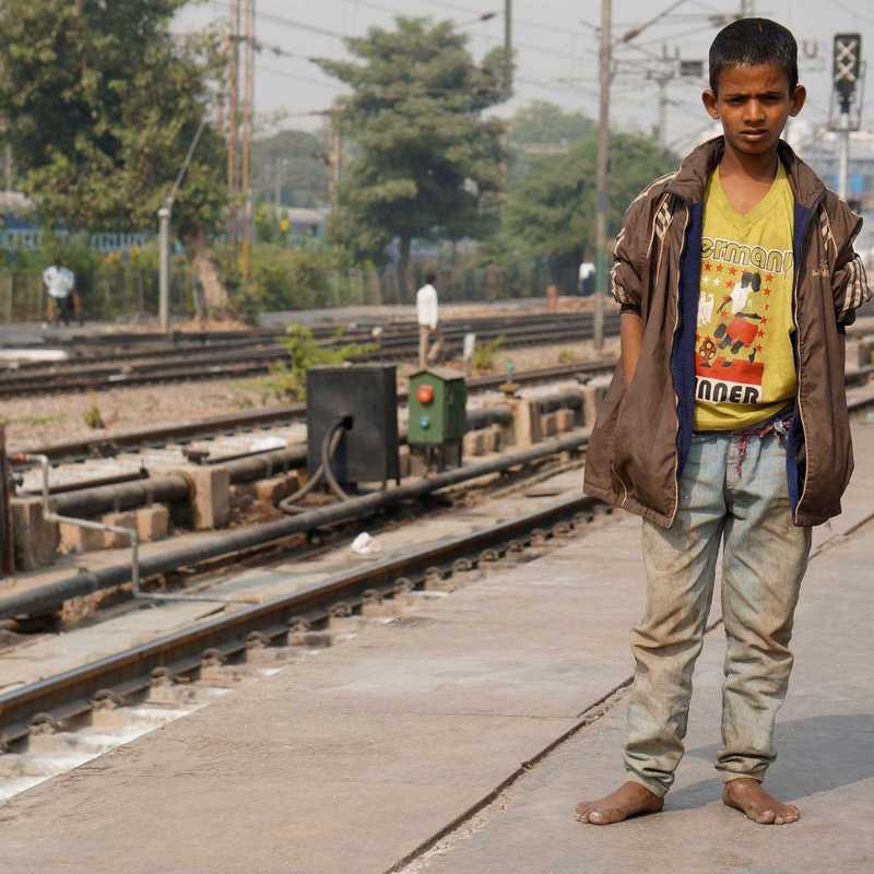 Straßenjunge in Indien an den Bahngleisen