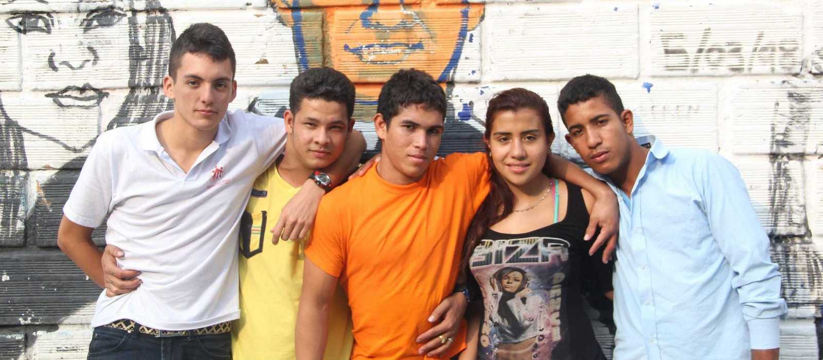 Jugendliche in der Ciudad Don Bosco vor einem Grafiti von Don Bosco