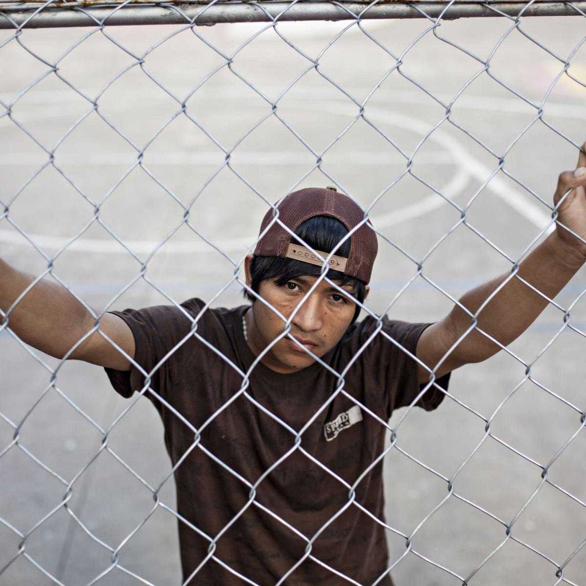 Straßenkind in Bolivien steht hinter einem Zaun