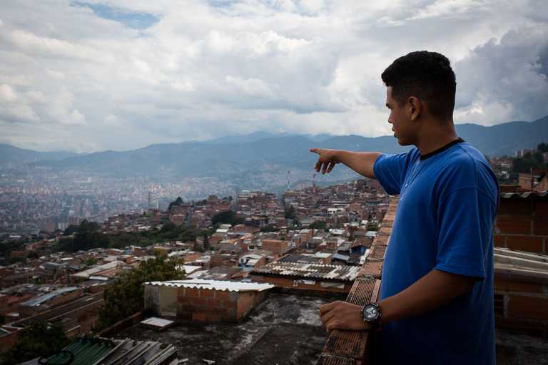 Jugendlicher zeigt auf die Stadt Medellín