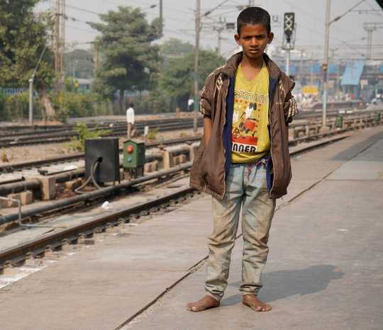 Straßenjunge in Indien an den Bahngleisen