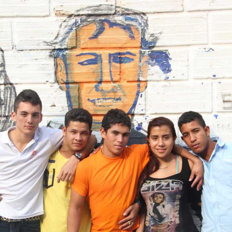 Jugendliche in der Ciudad Don Bosco vor einem Grafiti von Don Bosco
