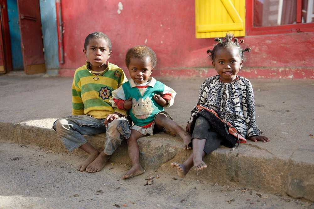 Drei kleine Kinder sitzen am Straßenrand