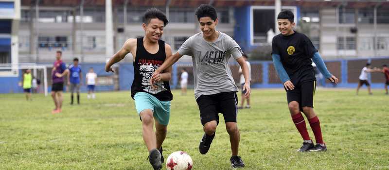 drei Jugendliche beim Fußball spielen