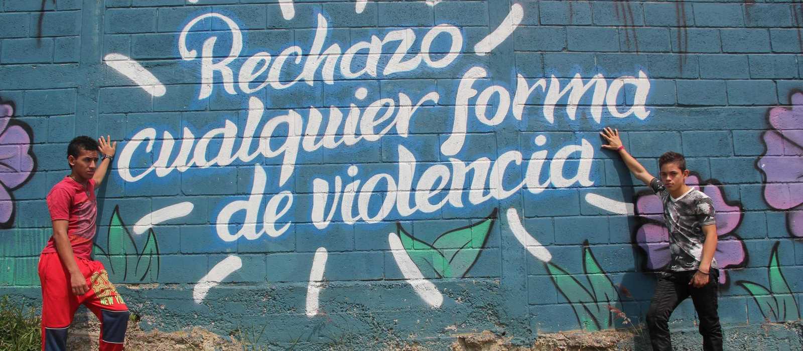 zwei Jungs vor einem Grafiti das besagt: Jede Form von Gewal ablehnen