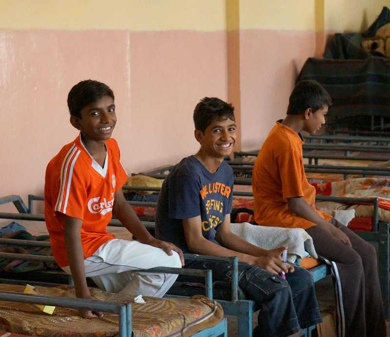Vier Jungs sitzen auf den Betten im Straßenkinderzentrum in Delhi