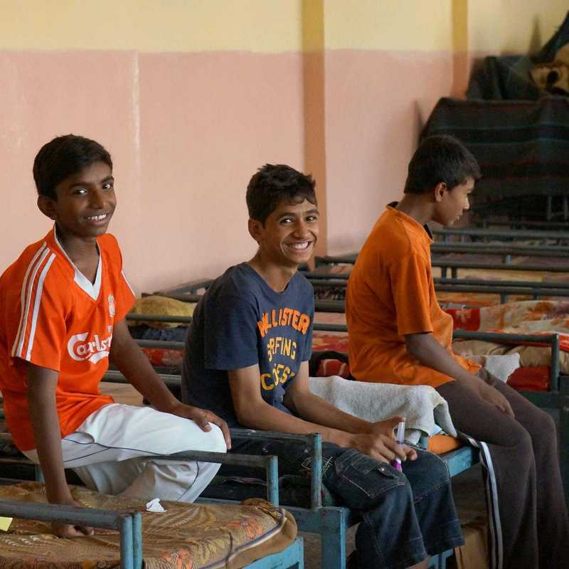 Vier Jungs sitzen auf den Betten im Straßenkinderzentrum in Delhi