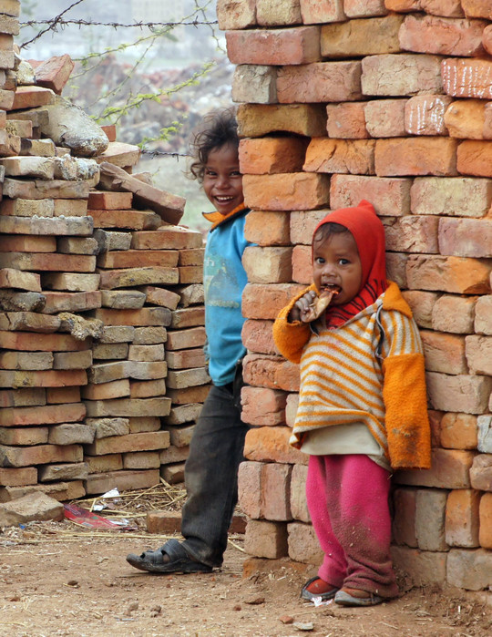 Drei Kinder stehen zwischen den Ziegelmauern in Passor