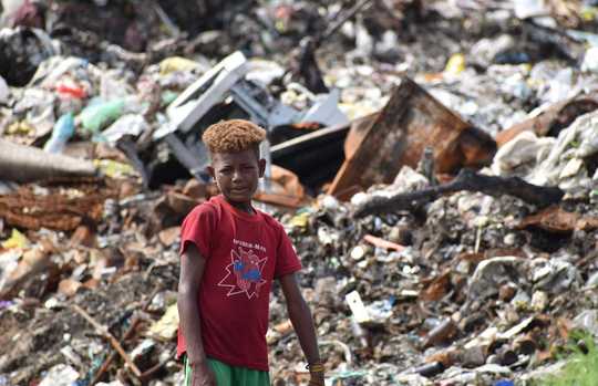 Junge steht vor einem Müllberg